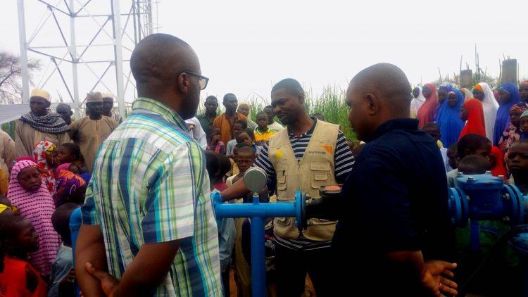 水資源暨衛生計畫專員哈米蘇(中間穿背心者)，在塔瓦計畫區向居民介紹台灣愛心支持的水資源建設。(台灣世界展望會提供)