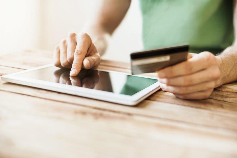 man holding a credit card in front of an ipad