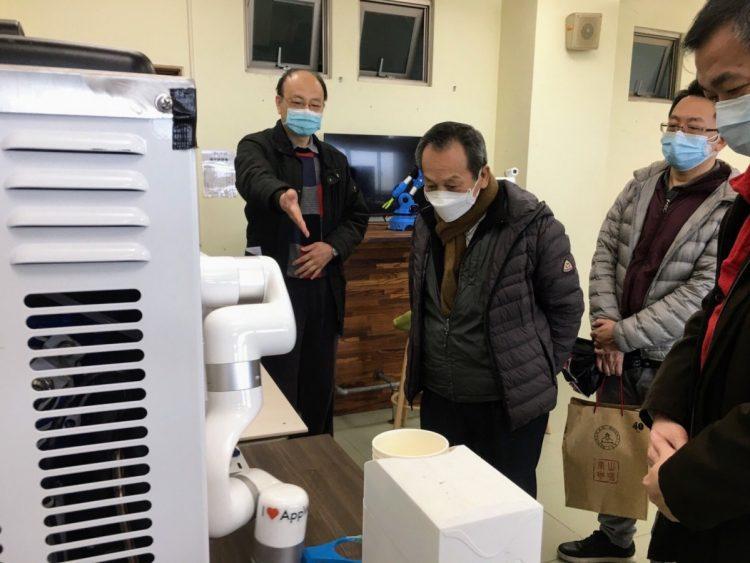 游啟明董事長（左二）參觀工業管理系的機器手臂咖啡機。