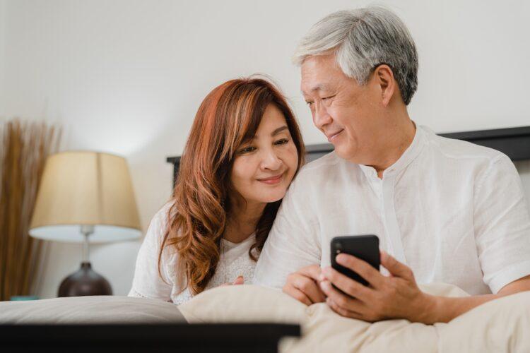 asian-senior-couple-using-mobile-phone-home-asian-senior-chinese-grandparents-husband-wife-happy-after-wake-up-watching-movie-lying-bed-bedroom-home-morning-concept